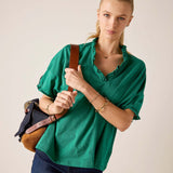 Woman wearing a green blouse with a plain background