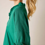 Green dress with ruffled details on a plain background