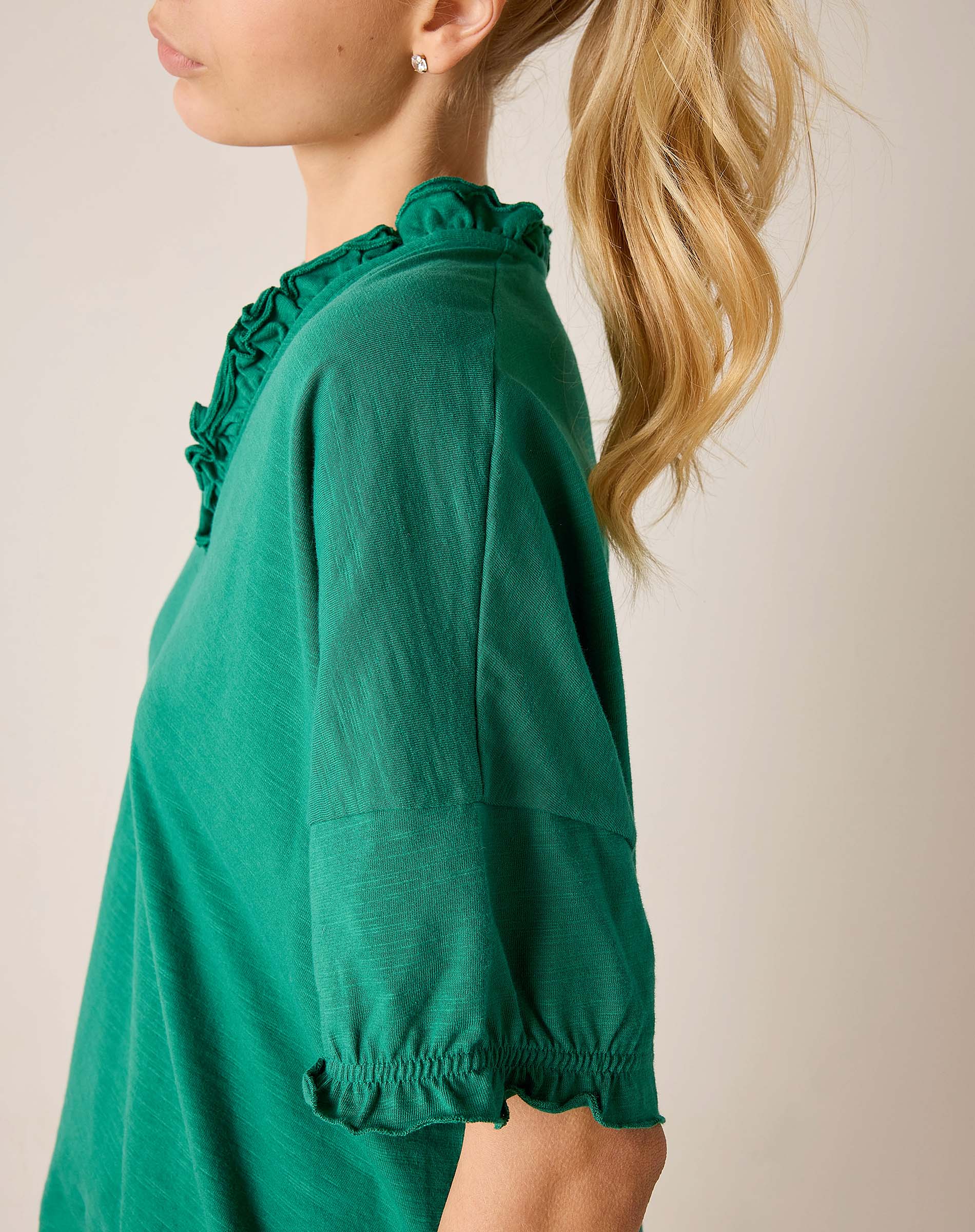 Green dress with ruffled details on a plain background