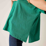 Green shirt worn by a person on a plain background