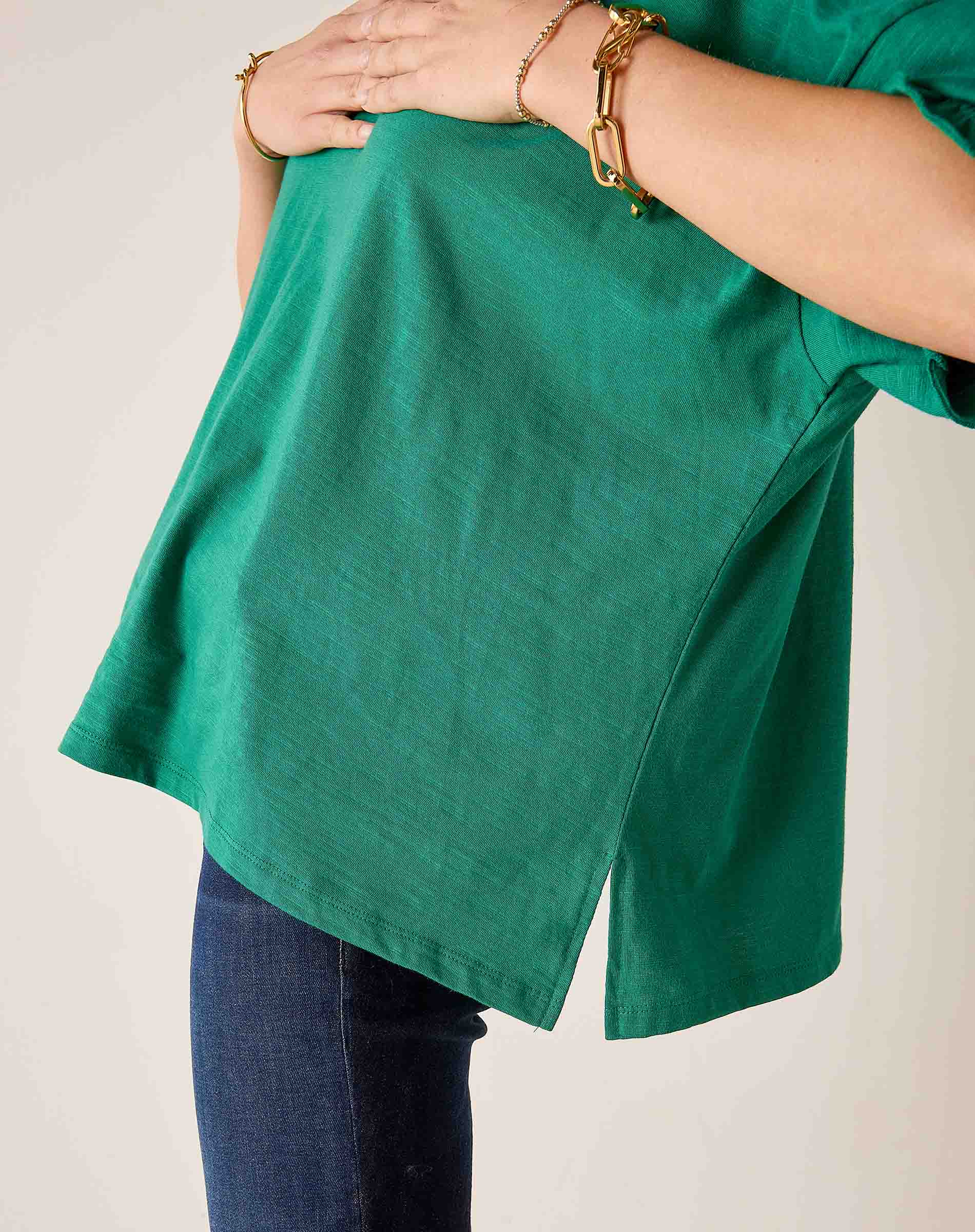 Green shirt worn by a person on a plain background