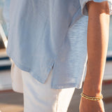 Person wearing a light blue shirt and white shorts with a blurred background