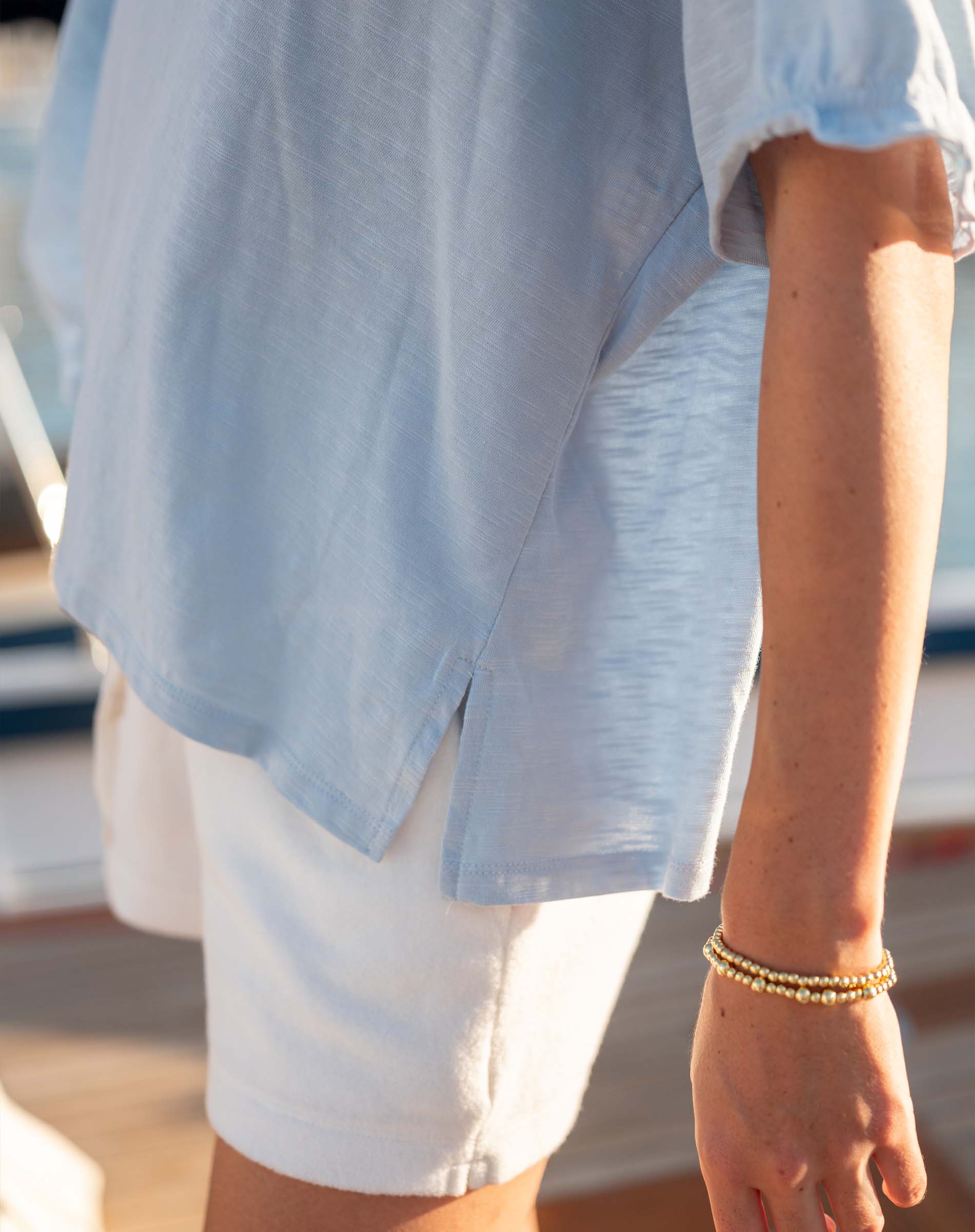 Person wearing a light blue shirt and white shorts with a blurred background