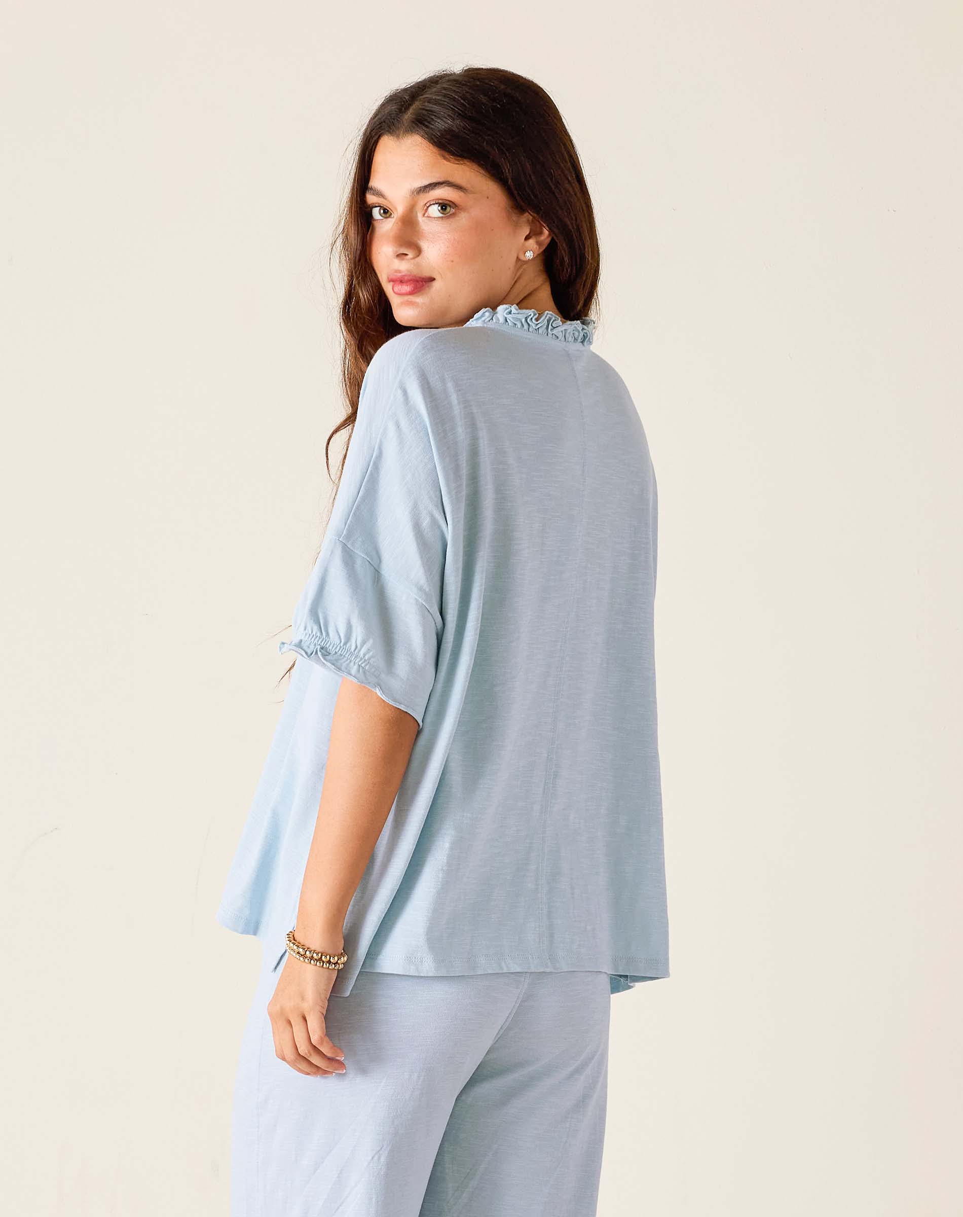 Woman wearing a light blue outfit with a plain background