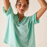 Woman wearing a light green blouse with ruffled neckline against a plain background