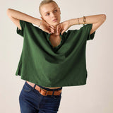 Model wearing an oversized pine green ruffled tee with short sleeves and dark denim jeans.