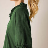 Model in a pine green ruffle tee with ruffled edges along the neckline and sleeve cuffs.