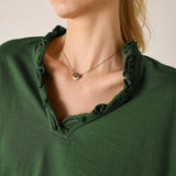 Model wearing a pine green ruffle tee with a scoop neckline and soft, draped fabric texture.