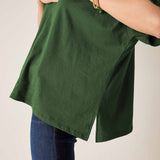 Model wearing an oversized pine green ruffle tee in a textured fabric, paired with blue denim jeans.