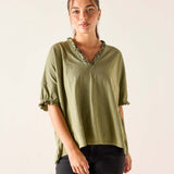 Woman wearing an olive green blouse with a plain background