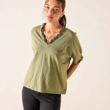 Woman wearing a green blouse with ruffled details on a plain background
