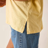 Person wearing a yellow shirt and blue shorts on a plain background