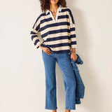 Woman wearing a striped sweater and jeans against a plain background