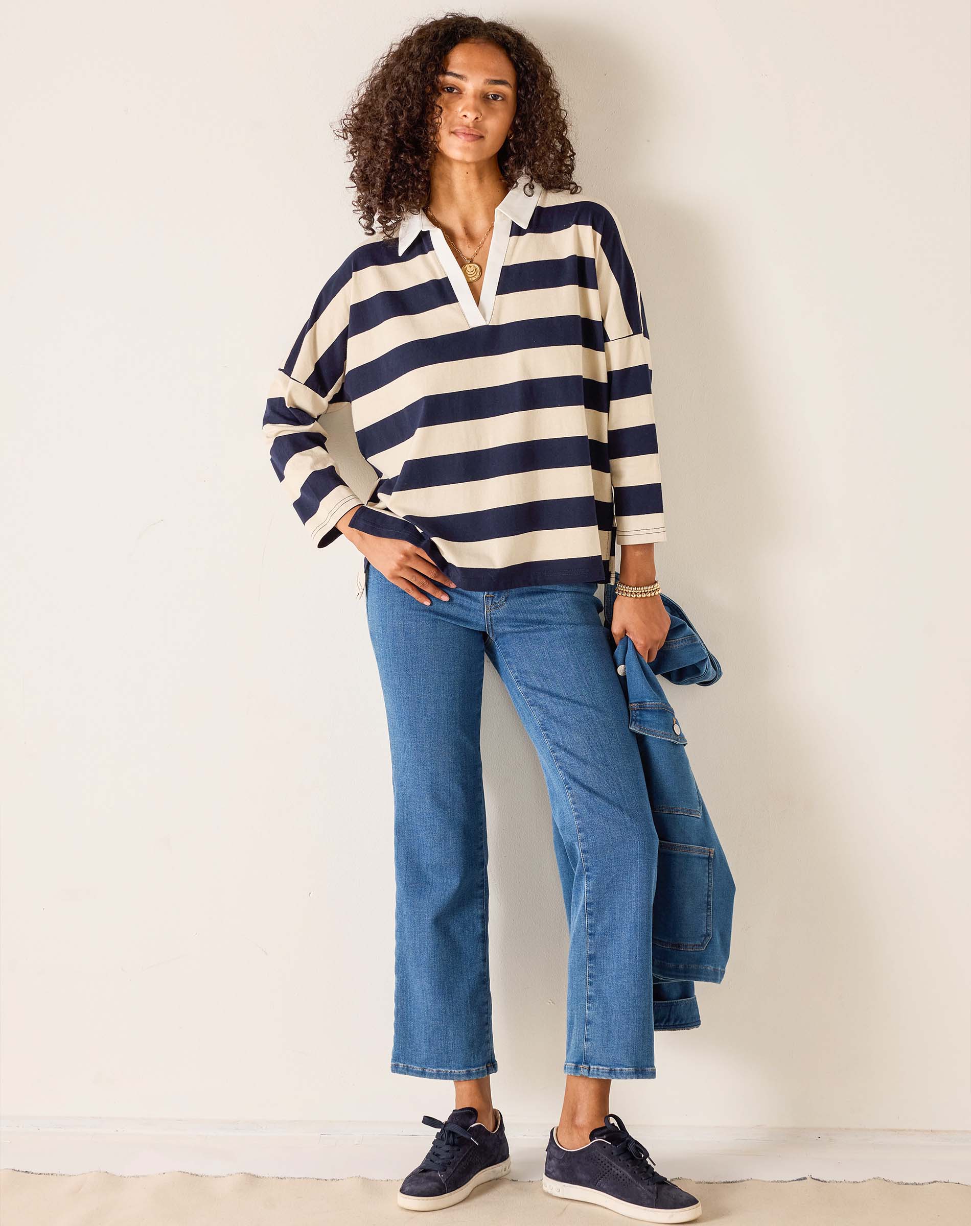 Woman wearing a striped sweater and jeans against a plain background