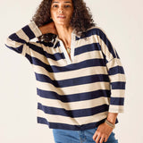 Woman wearing a navy and white striped shirt with blue jeans on a plain background