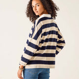 Woman wearing a navy and white striped sweater with blue jeans on a plain background