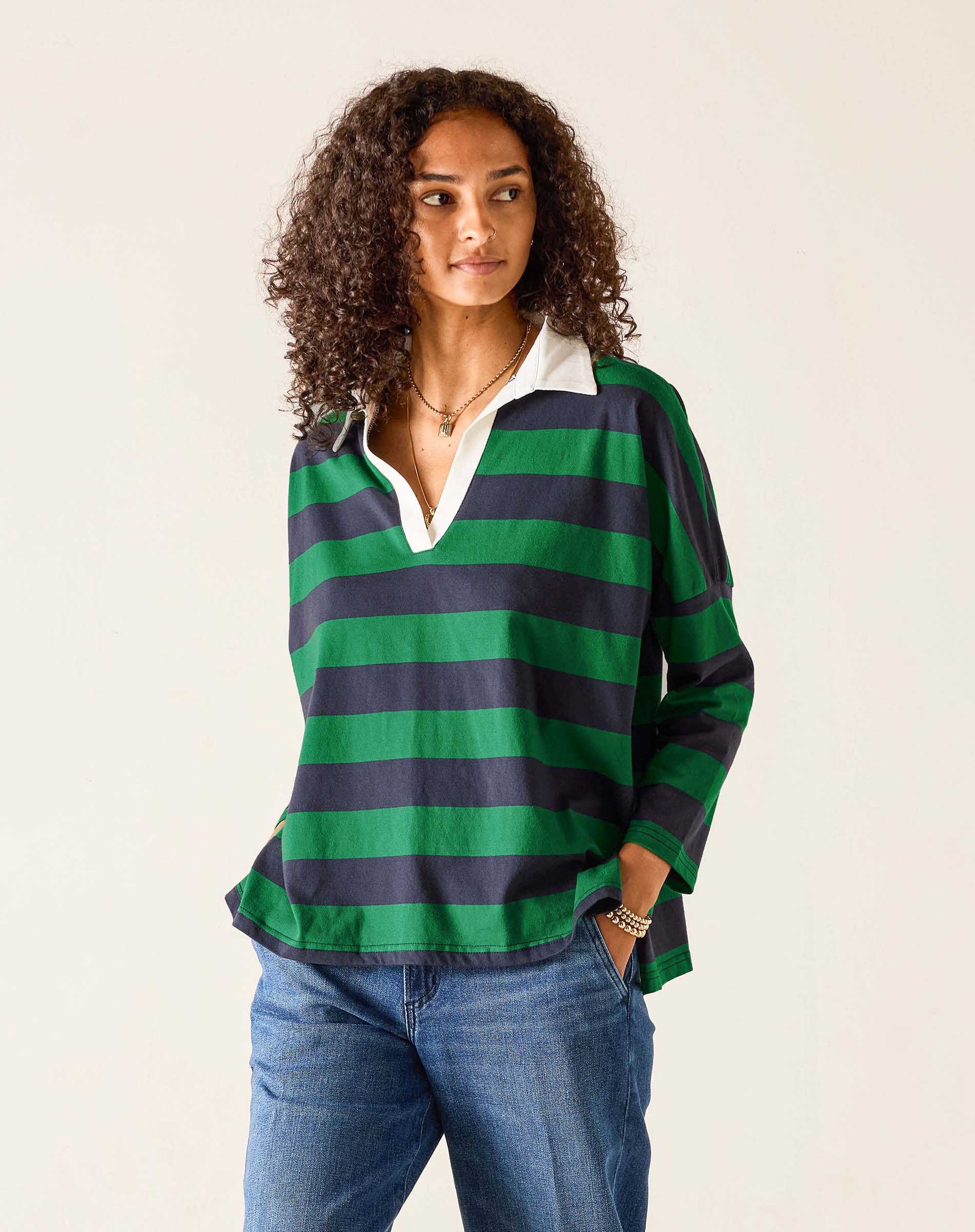 Woman wearing a green and navy striped shirt with a white collar on a beige background