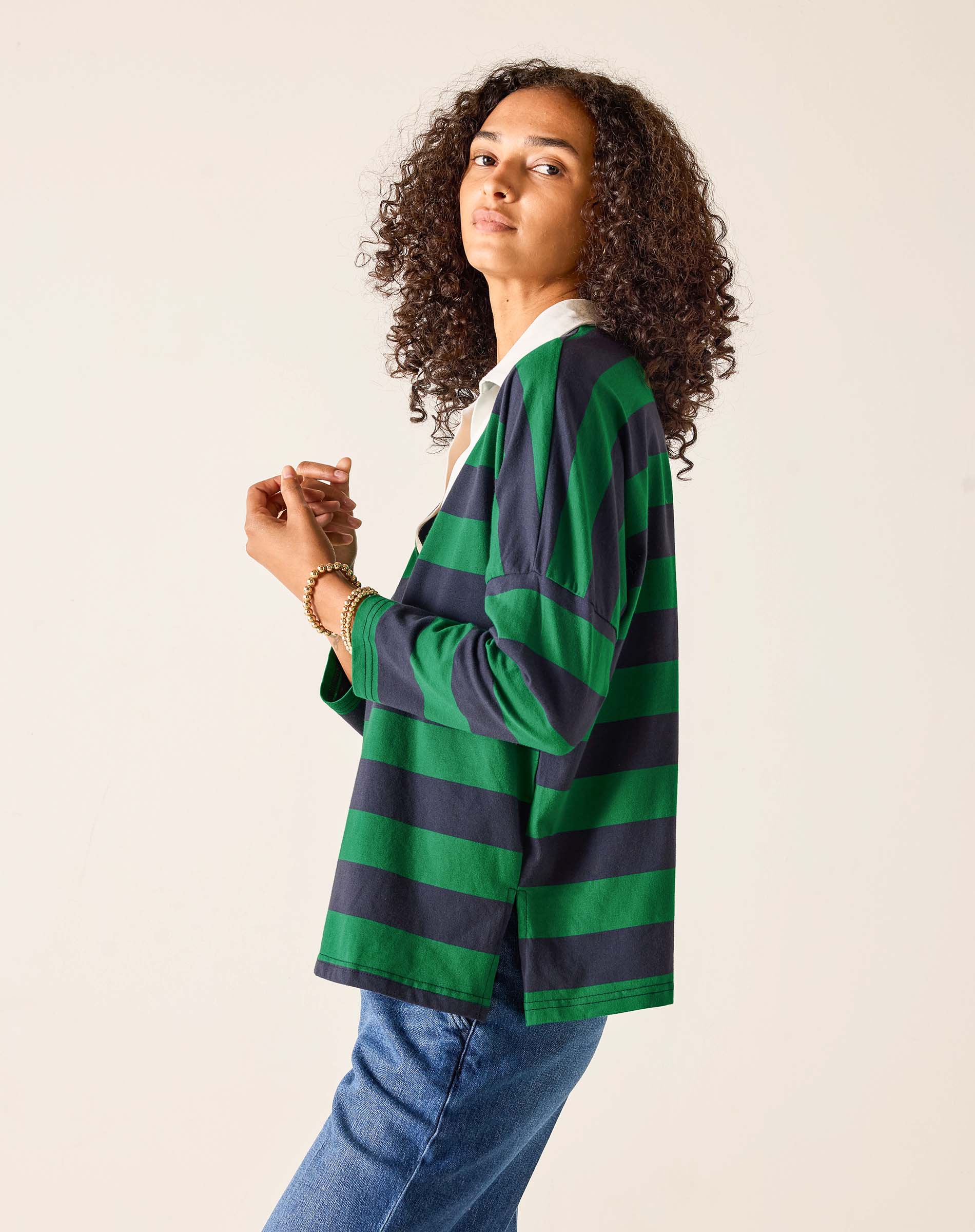Person wearing a green and navy striped cardigan on a beige background