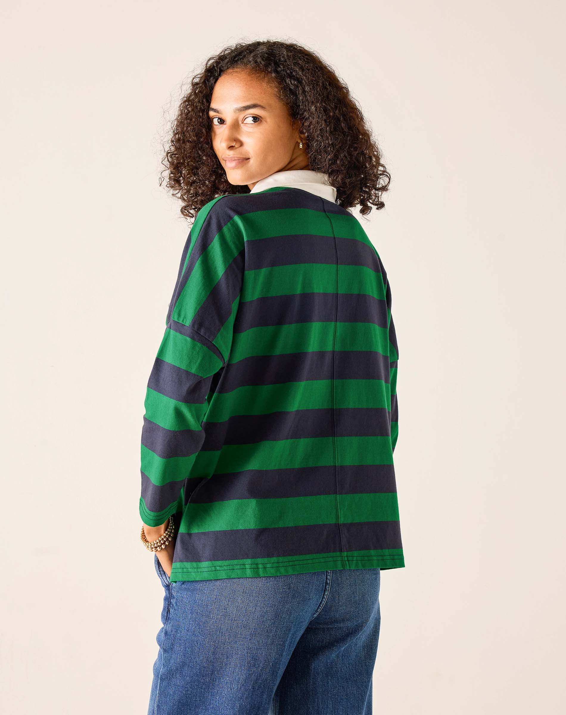 Person wearing a green and navy striped shirt on a beige background