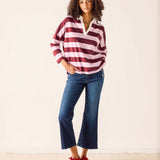 Woman wearing a red and white striped shirt with blue jeans on a plain background