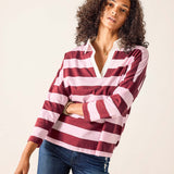 Woman wearing a red and white striped shirt with blue jeans on a beige background