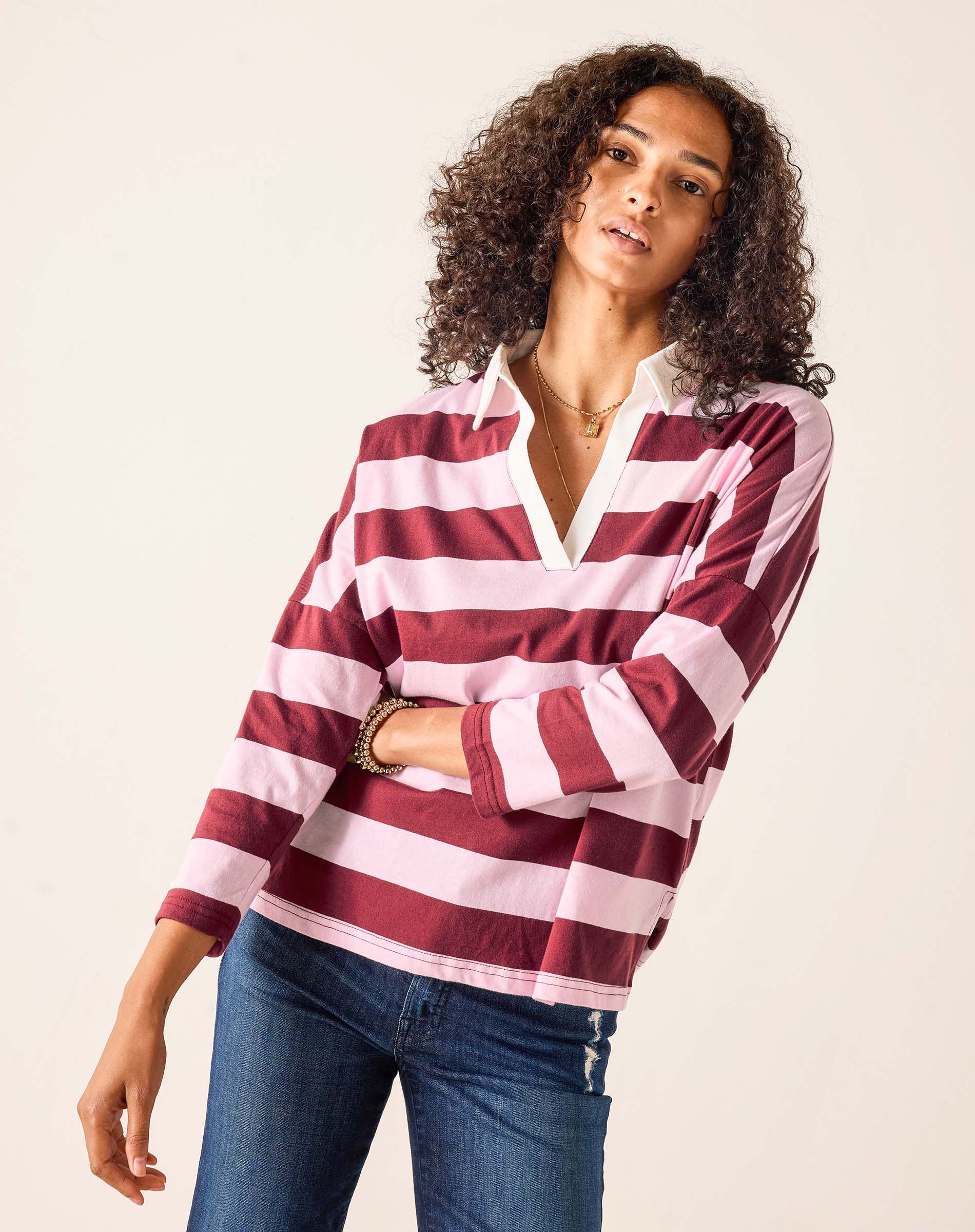 Woman wearing a red and white striped shirt with blue jeans on a beige background