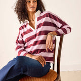 Woman wearing a red and white striped shirt sitting on a wooden chair.