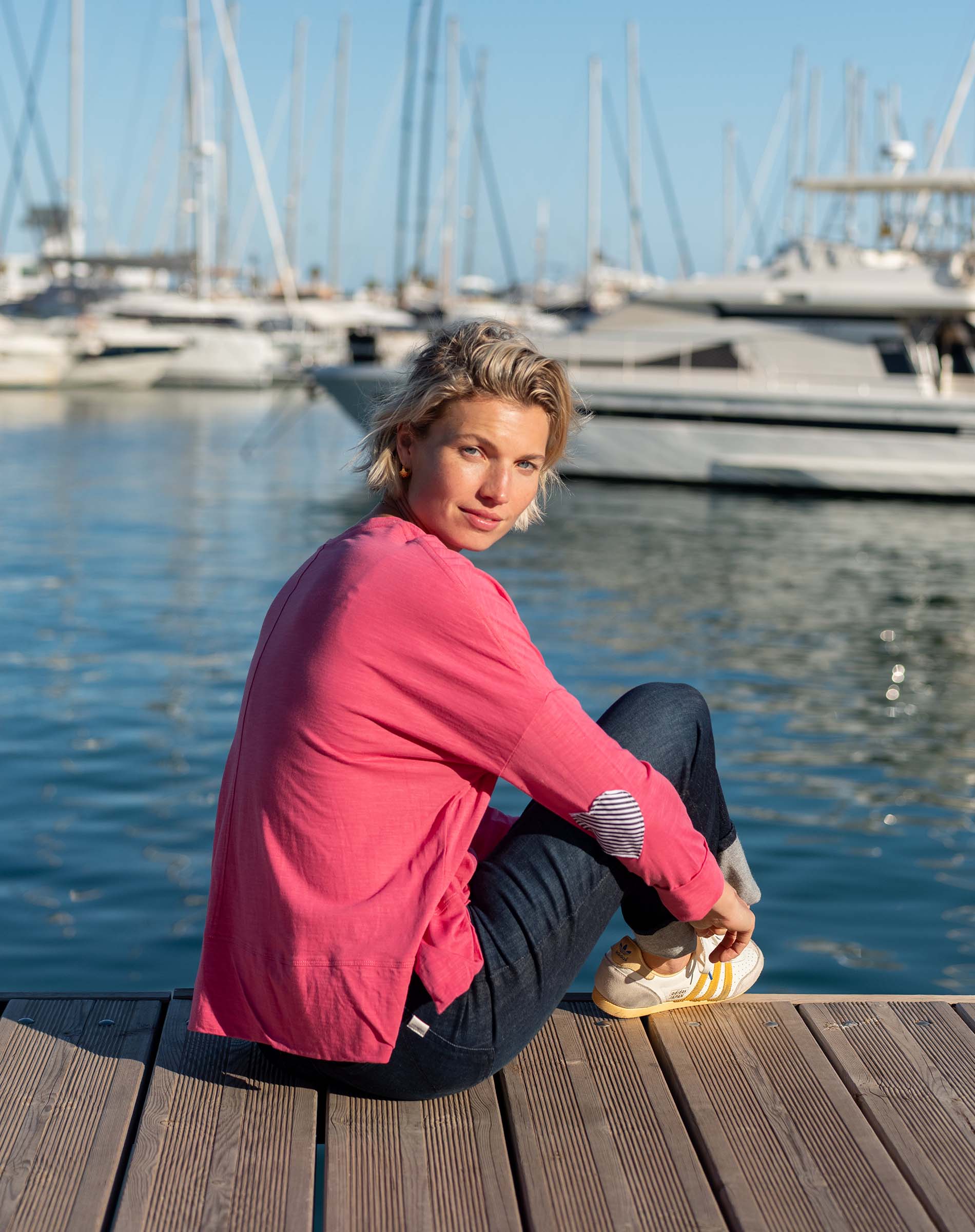 Rose pink t-shirt with navy striped and heart applique details on a model at a harbor.