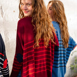 female wearing maroon and red striped sweater in front of white wall with friends