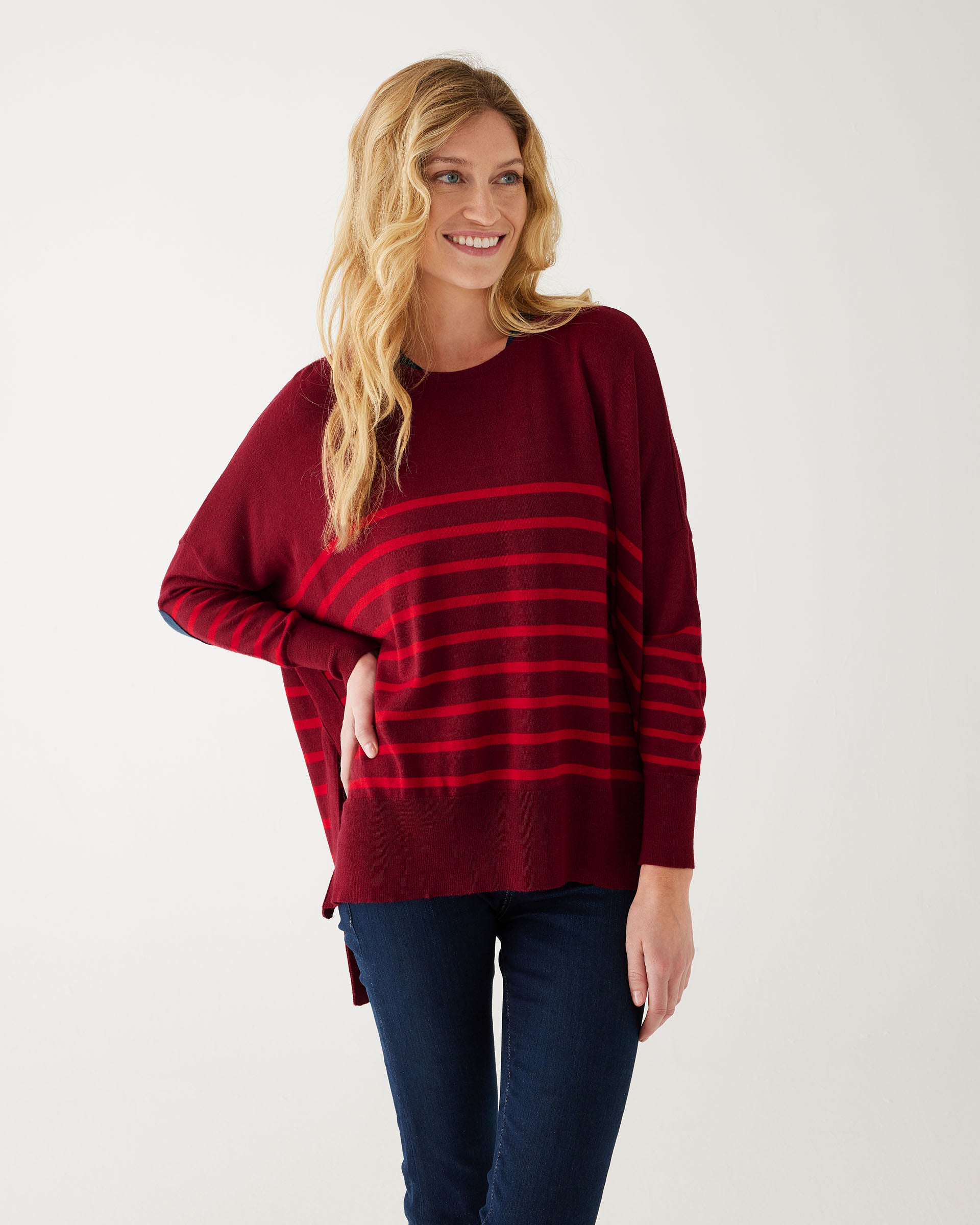 maroon sweater with red stripes and a navy heart elbow patch with dark jeans on white background