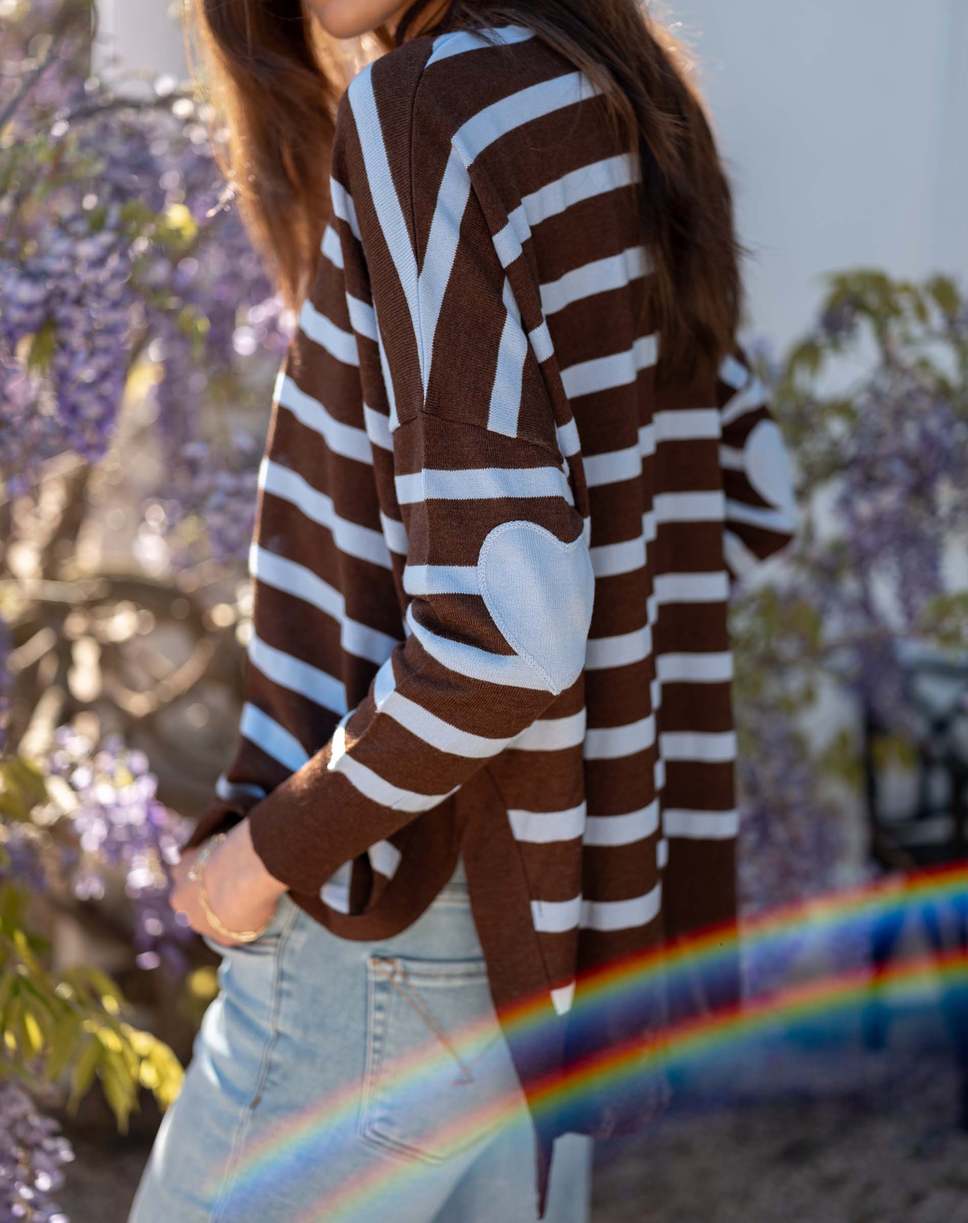Side view of a chocolate icing brown and blue oversized knit sweater with wide stripes.