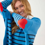 female wearing blue sweater with navy stripes and a red heart elbow patch on white background