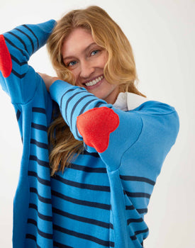 female wearing blue sweater with navy stripes and a red heart elbow patch on white background
