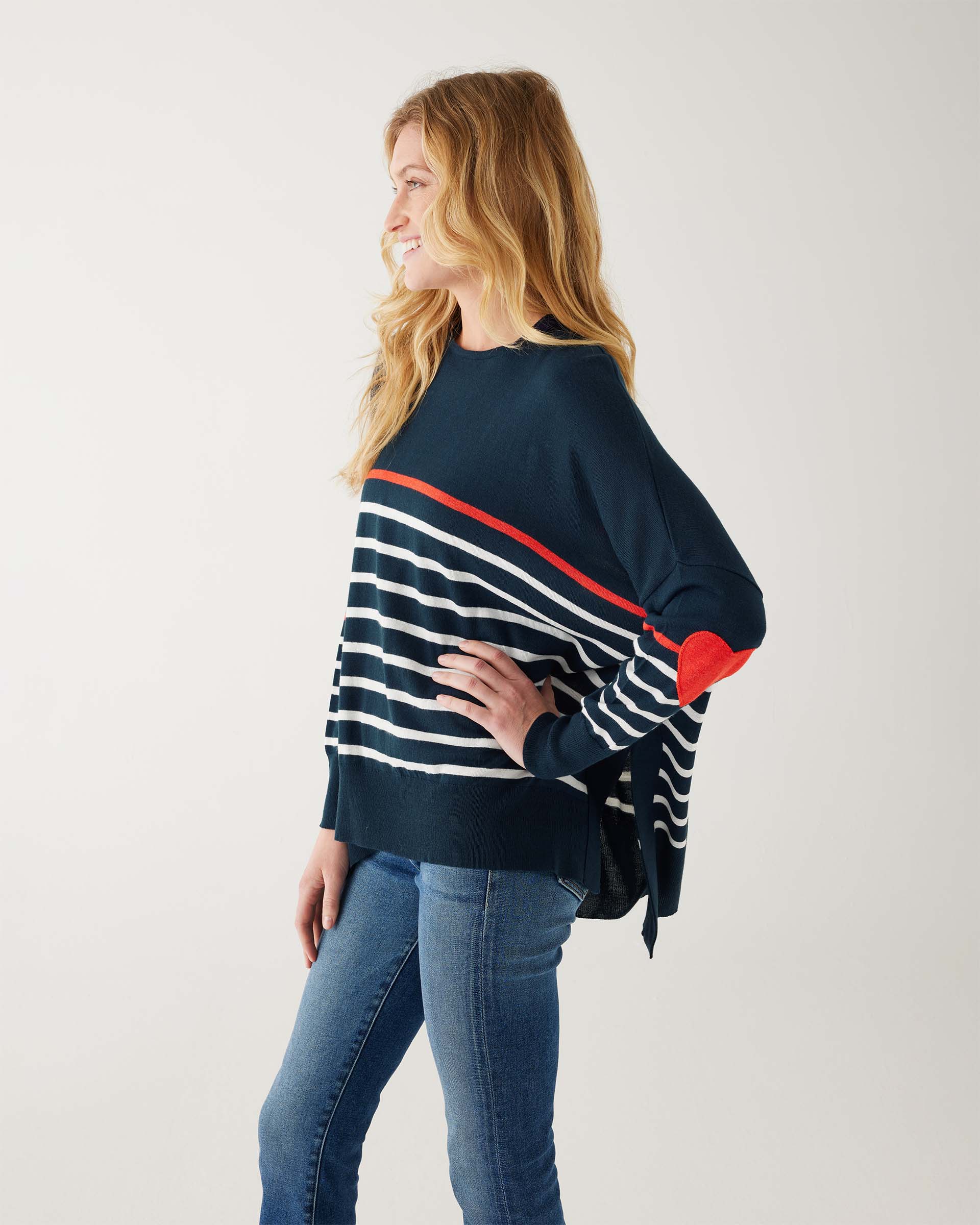 female wearing navy sweater with white stripes & red heart elbow patch sideways on white background