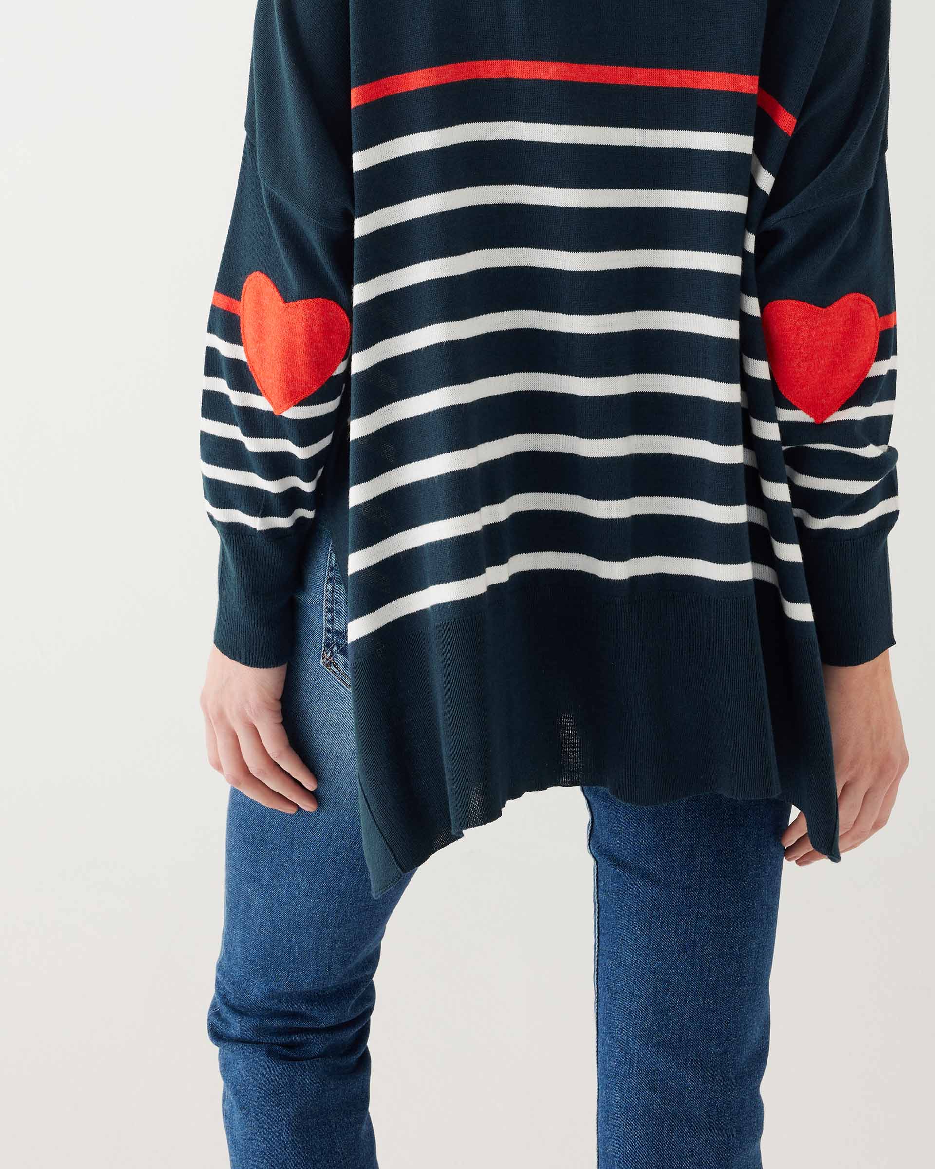 female wearing navy sweater with white stripes & red heart elbow patch backward on white background