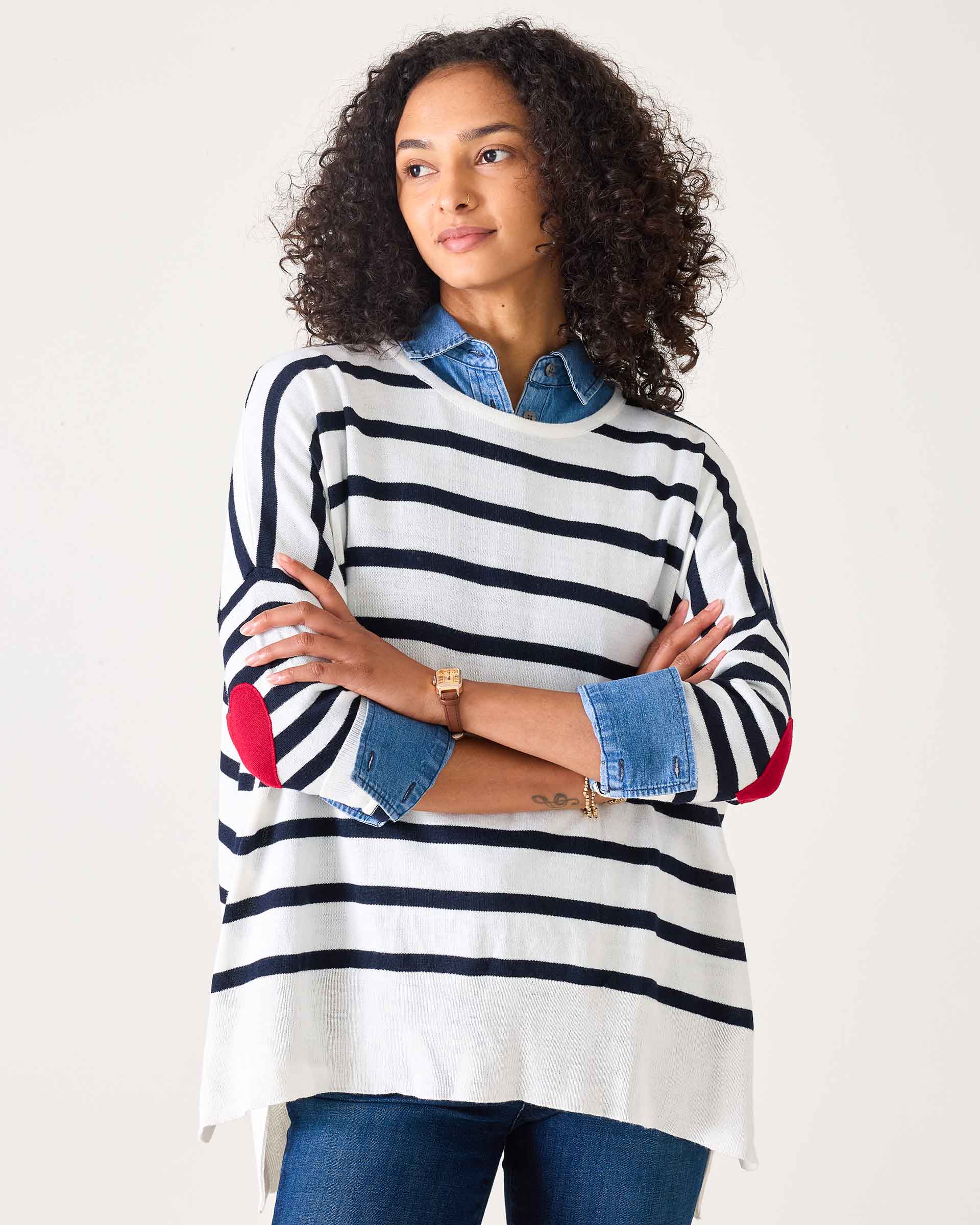 Woman wearing a striped sweater with rolled-up sleeves on a plain background