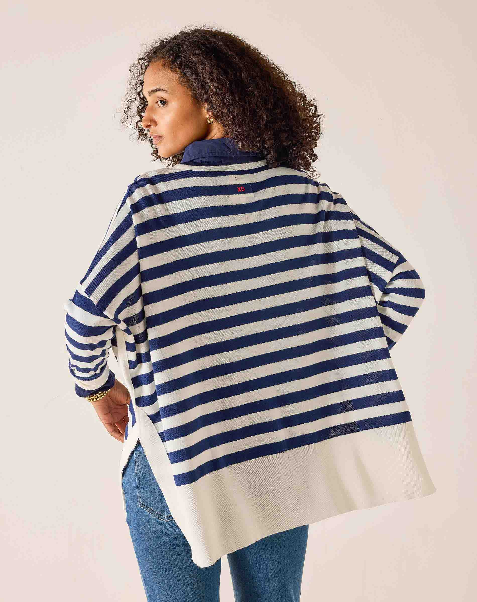 Woman wearing a blue and white striped sweater with a visible brand logo on a plain background