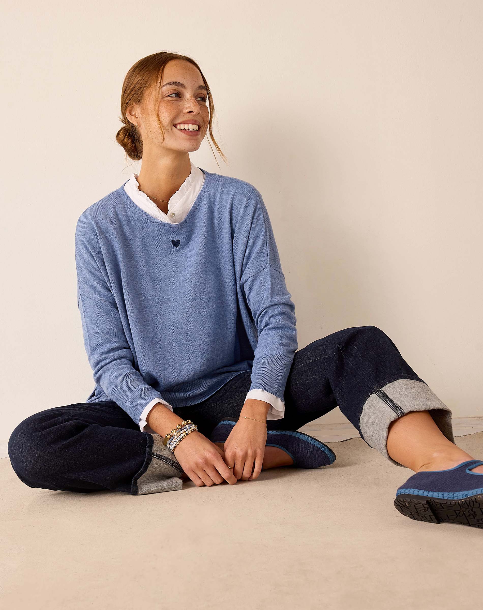 Ocean blue knit sweater with a small heart detail and high-waisted navy pants with cuffed hems.