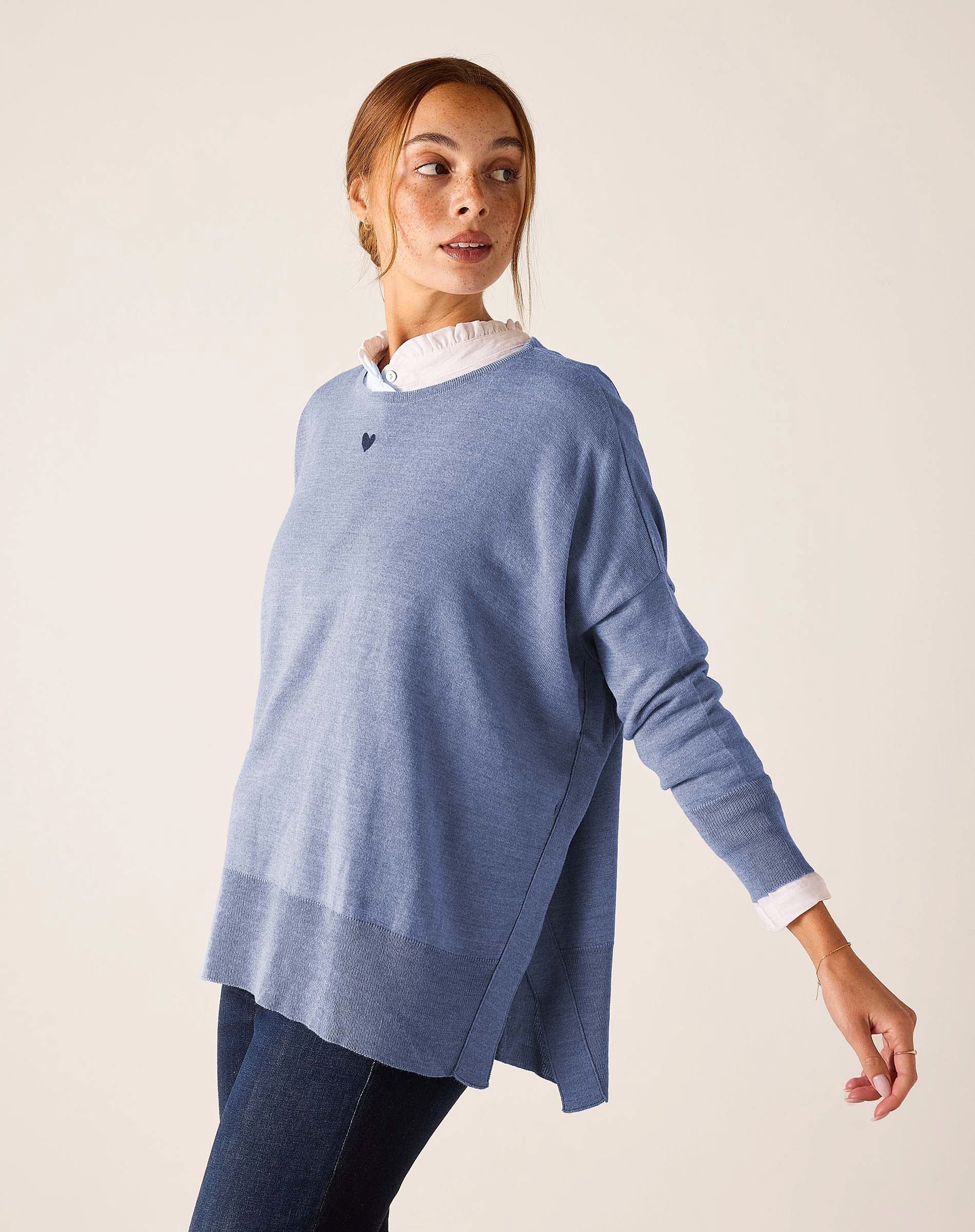 Ocean blue knit sweater with a split side hem and long sleeves over a white shirt.