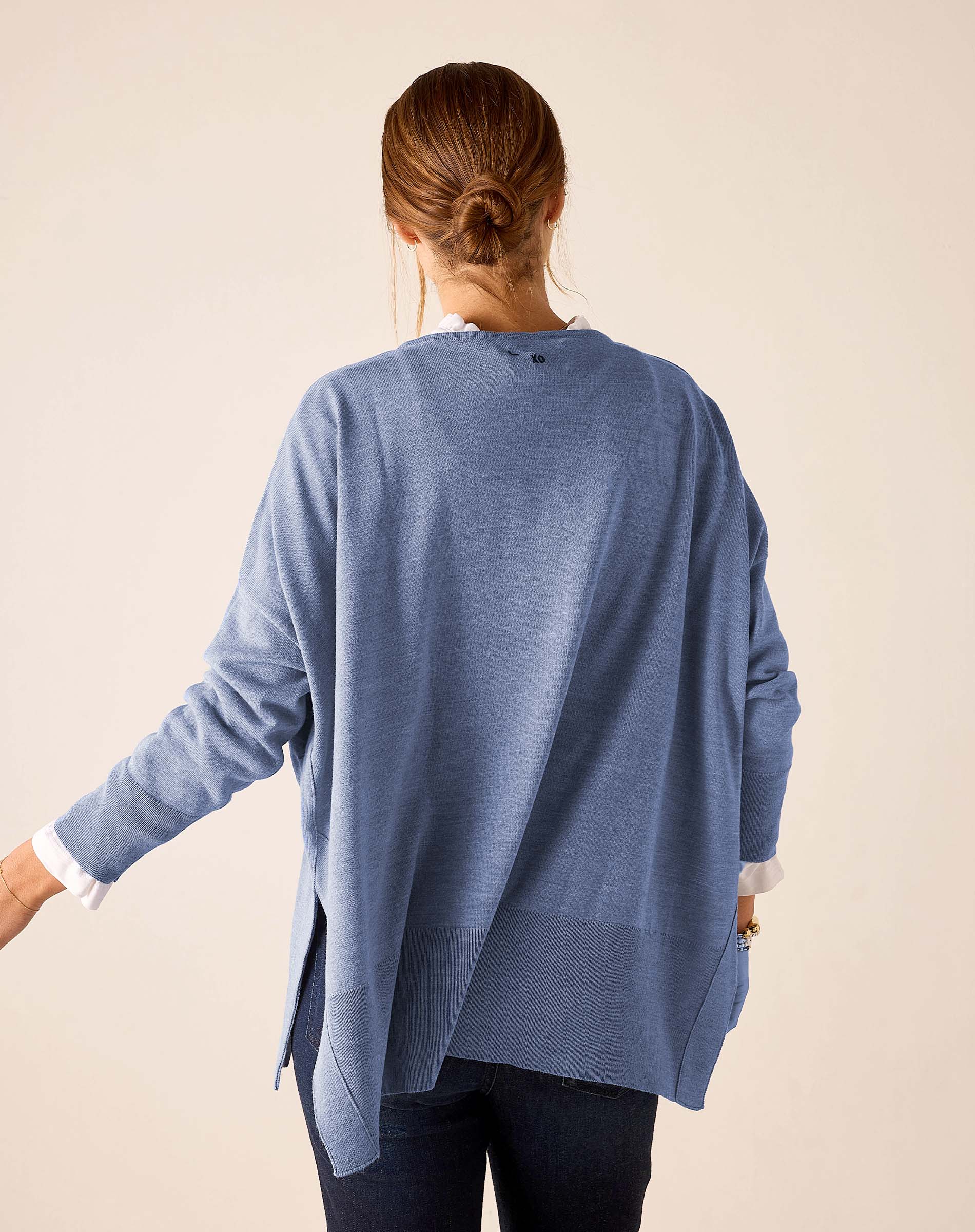 Back view of the ocean blue knit sweater with a relaxed fit and side slits.