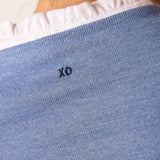 Ocean blue knit sweater with a ruffled white collar detail and 'XO' embroidered on the front.