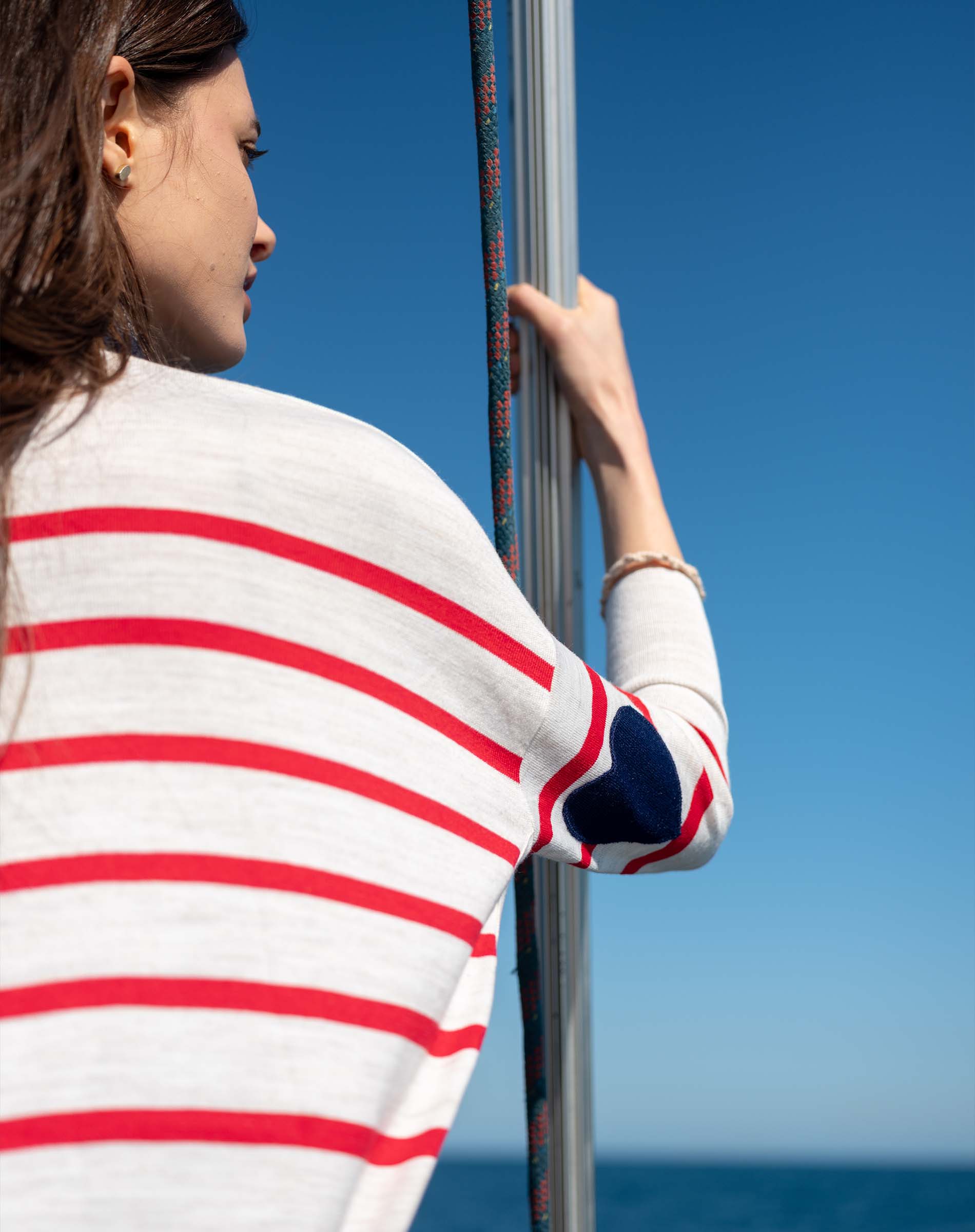 Side view of the MERSEA red and white striped knit sweater with a navy heart detail on the sleeve.