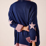 Navy blue oversized knit sweater with red and white stripes and star details on the sleeves.