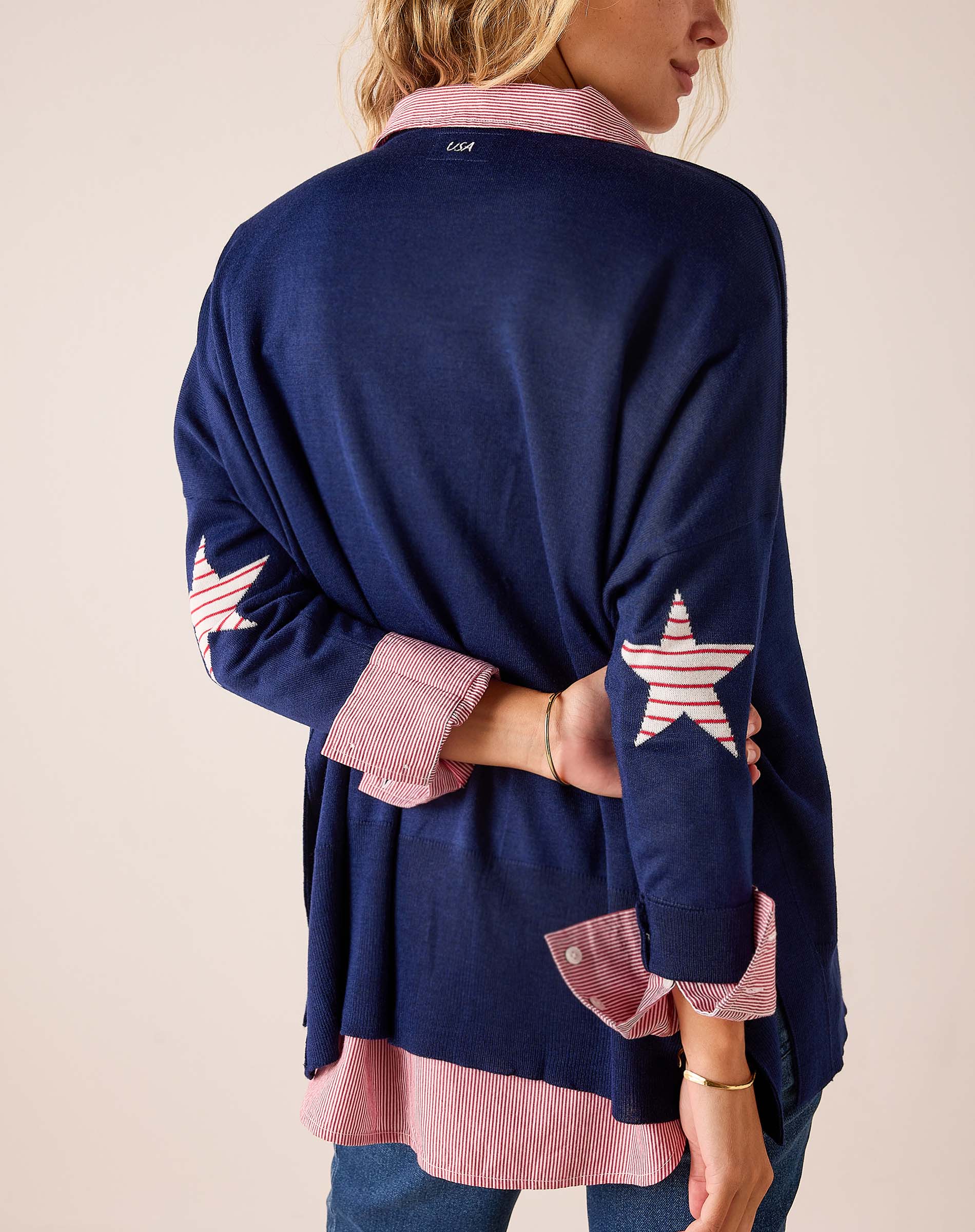 Navy blue oversized knit sweater with red and white stripes and star details on the sleeves.