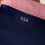 Navy blue knit sweater featuring a red and white striped collar detail with 'USA' embroidered on a small front pocket.