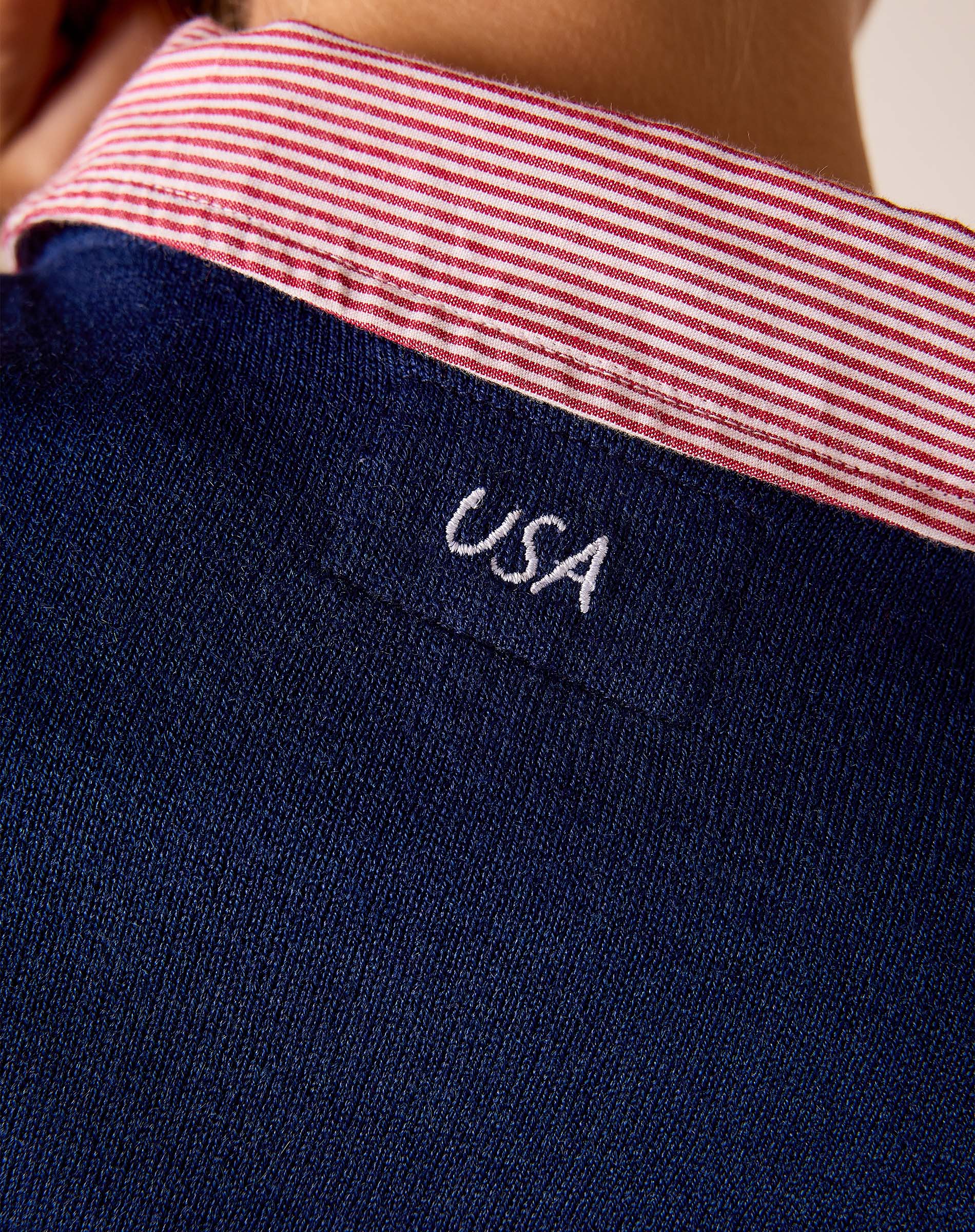 Navy blue knit sweater featuring a red and white striped collar detail with 'USA' embroidered on a small front pocket.