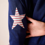 Navy blue knit sweater featuring a large red and white striped star on the sleeve.