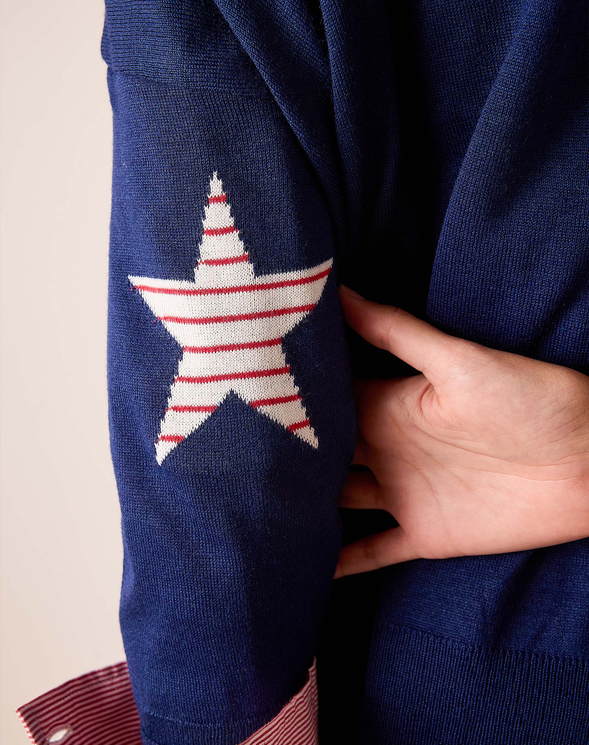 Navy blue knit sweater featuring a large red and white striped star on the sleeve.