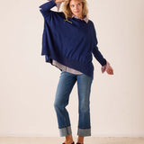Navy blue oversized knit sweater with stars and stripes detail layered over a patterned button-down shirt.
