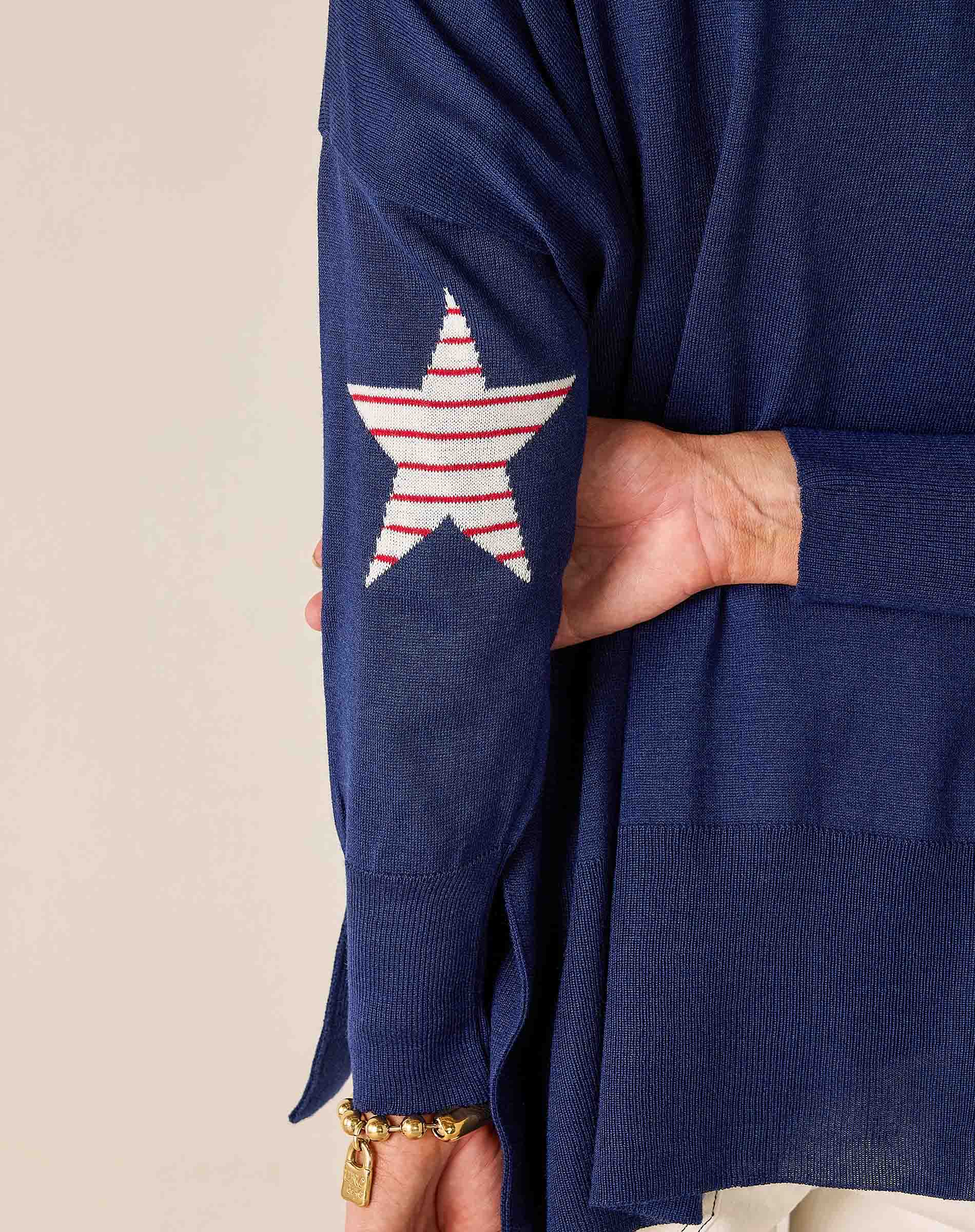 Navy blue sweater with a star design on the sleeve against a beige background